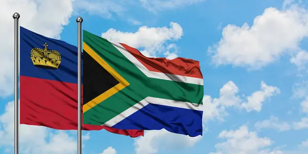 Vlajka Lichtenštejnska a Jihoafrické republiky mávajících větrem proti bílé zamračené modré obloze. Diplomacie, mezinárodní vztahy. — Stock fotografie