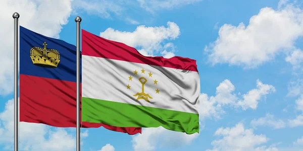 Bandera de Liechtenstein y Tayikistán ondeando en el viento contra el cielo azul nublado blanco juntos. Concepto diplomático, relaciones internacionales . — Foto de Stock