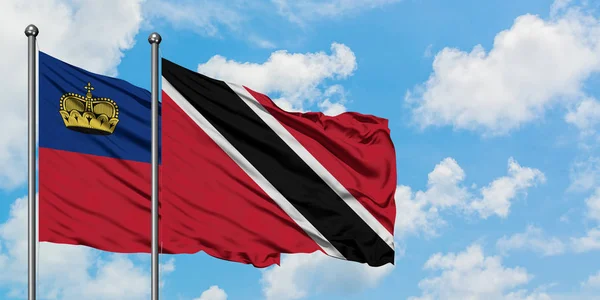 Liechtenstein ve Trinidad ve Tobago bayrağı birlikte beyaz bulutlu mavi gökyüzüne karşı rüzgarda sallayarak. Diplomasi kavramı, uluslararası ilişkiler. — Stok fotoğraf