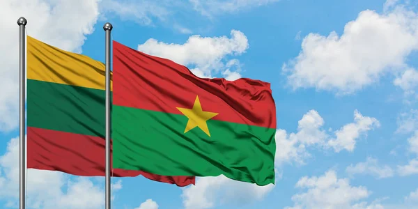 Bandera de Lituania y Burkina Faso ondeando en el viento contra el cielo azul nublado blanco juntos. Concepto diplomático, relaciones internacionales . — Foto de Stock