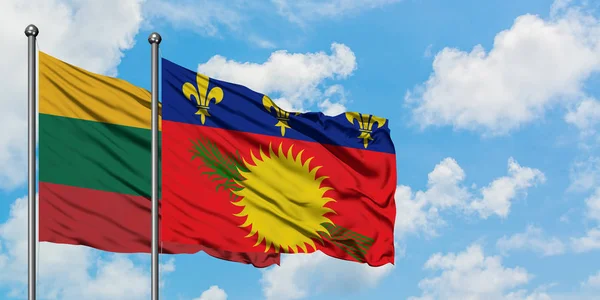 Bandera de Lituania y Guadalupe ondeando en el viento contra el cielo azul nublado blanco juntos. Concepto diplomático, relaciones internacionales . — Foto de Stock