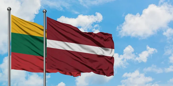 Lituania e Lettonia bandiera sventolando nel vento contro bianco cielo blu nuvoloso insieme. Concetto di diplomazia, relazioni internazionali . — Foto Stock