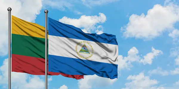Bandera de Lituania y Nicaragua ondeando en el viento contra el cielo azul nublado blanco juntos. Concepto diplomático, relaciones internacionales . — Foto de Stock