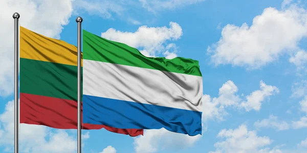 Bandera de Lituania y Sierra Leona ondeando en el viento contra el cielo azul nublado blanco juntos. Concepto diplomático, relaciones internacionales . — Foto de Stock