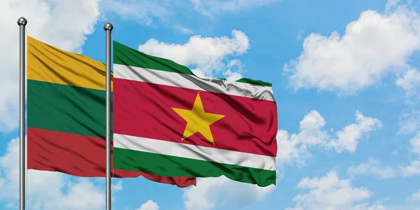 Bandera de Lituania y Surinam ondeando en el viento contra el cielo azul nublado blanco juntos. Concepto diplomático, relaciones internacionales . — Foto de Stock