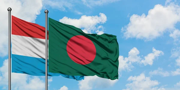 Bandera de Luxemburgo y Bangladesh ondeando en el viento contra el cielo azul nublado blanco juntos. Concepto diplomático, relaciones internacionales . — Foto de Stock