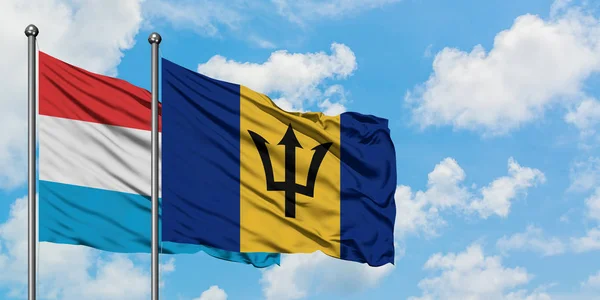 卢森堡和巴巴多斯国旗在风中飘扬，与白云蓝天相一起。外交概念、国际关系. — 图库照片
