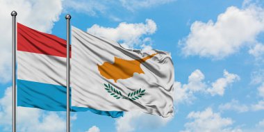 Lüksemburg ve Kıbrıs bayrağı birlikte beyaz bulutlu mavi gökyüzüne karşı rüzgarda sallayarak. Diplomasi kavramı, uluslararası ilişkiler.