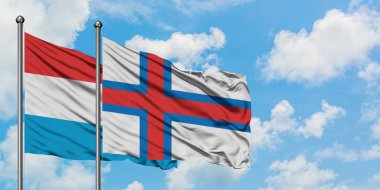 Lüksemburg ve Faroe Adaları bayrağı birlikte beyaz bulutlu mavi gökyüzüne karşı rüzgarsal sallayarak. Diplomasi kavramı, uluslararası ilişkiler.