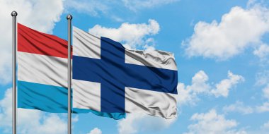 Lüksemburg ve Finlandiya bayrağı birlikte beyaz bulutlu mavi gökyüzüne karşı rüzgarsal sallayarak. Diplomasi kavramı, uluslararası ilişkiler.