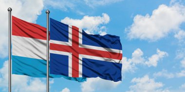 Lüksemburg ve İzlanda bayrağı birlikte beyaz bulutlu mavi gökyüzüne karşı rüzgarda sallayarak. Diplomasi kavramı, uluslararası ilişkiler.