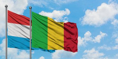 Lüksemburg ve Mali bayrağı birlikte beyaz bulutlu mavi gökyüzüne karşı rüzgarda sallayarak. Diplomasi kavramı, uluslararası ilişkiler.