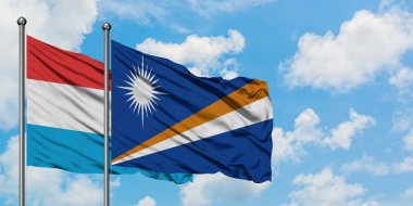 Lüksemburg ve Marshall Adaları bayrağı birlikte beyaz bulutlu mavi gökyüzüne karşı rüzgarda sallayarak. Diplomasi kavramı, uluslararası ilişkiler.