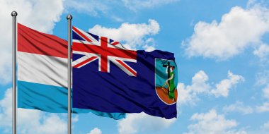 Lüksemburg ve Montserrat bayrağı birlikte beyaz bulutlu mavi gökyüzüne karşı rüzgarda sallayarak. Diplomasi kavramı, uluslararası ilişkiler.