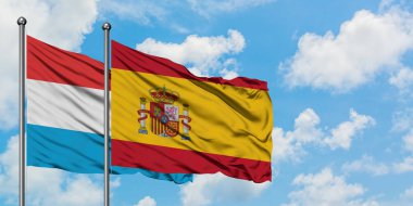 Lüksemburg ve İspanya bayrağı birlikte beyaz bulutlu mavi gökyüzüne karşı rüzgarsal sallayarak. Diplomasi kavramı, uluslararası ilişkiler.