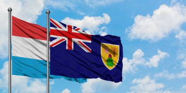 Lüksemburg ve Turks ve Caicos Adaları bayrağı birlikte beyaz bulutlu mavi gökyüzüne karşı rüzgarsal sallayarak. Diplomasi kavramı, uluslararası ilişkiler.