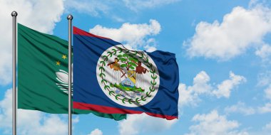 Macao ve Belize bayrağı birlikte beyaz bulutlu mavi gökyüzüne karşı rüzgarda sallayarak. Diplomasi kavramı, uluslararası ilişkiler.