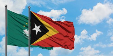 Macao ve Doğu Timor bayrağı birlikte beyaz bulutlu mavi gökyüzüne karşı rüzgarda sallayarak. Diplomasi kavramı, uluslararası ilişkiler.
