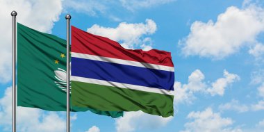 Macao ve Gambiya bayrağı birlikte beyaz bulutlu mavi gökyüzüne karşı rüzgarda sallayarak. Diplomasi kavramı, uluslararası ilişkiler.