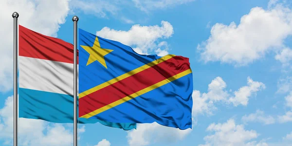 Bandera de Luxemburgo y Congo ondeando en el viento contra el cielo azul nublado blanco juntos. Concepto diplomático, relaciones internacionales . — Foto de Stock