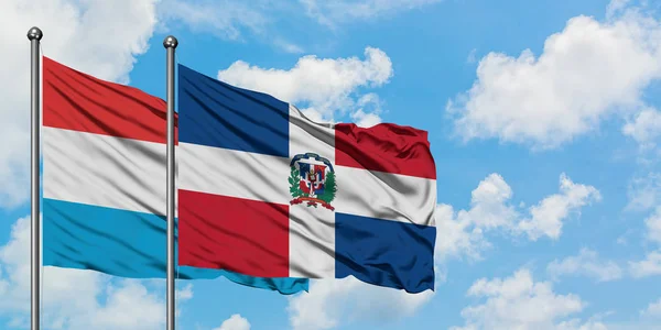 一緒に白い曇り青い空に対して風に手を振るルクセンブルクとドミニカ共和国の旗。外交概念、国際関係. — ストック写真