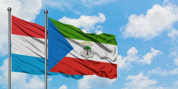 Bandera de Luxemburgo y Guinea Ecuatorial ondeando en el viento contra el cielo azul nublado blanco juntos. Concepto diplomático, relaciones internacionales . — Foto de Stock