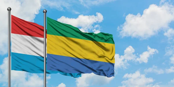 卢森堡和加蓬国旗在风中飘扬，白云蓝天相聚。外交概念、国际关系. — 图库照片