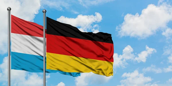 Luxemburg och Tyskland sjunker vifta i vinden mot vit grumlig blå himmel tillsammans. Diplomatisk koncept, internationella relationer. — Stockfoto