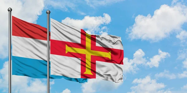 V Lucembursku a v Guernsey vlaje vlajka, která se ve větru vlnil proti bílé zamračené modré obloze. Diplomacie, mezinárodní vztahy. — Stock fotografie