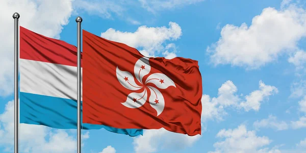 Bandera de Luxemburgo y Hong Kong ondeando en el viento contra el cielo azul nublado blanco juntos. Concepto diplomático, relaciones internacionales . —  Fotos de Stock