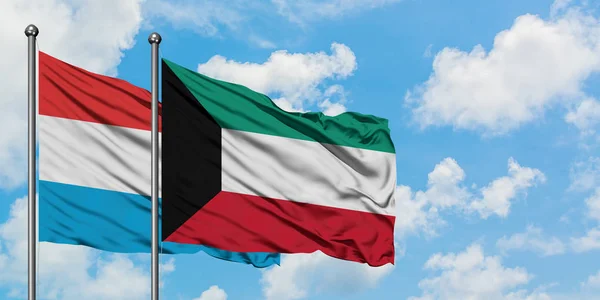 Bandera de Luxemburgo y Kuwait ondeando en el viento contra el cielo azul nublado blanco juntos. Concepto diplomático, relaciones internacionales . — Foto de Stock