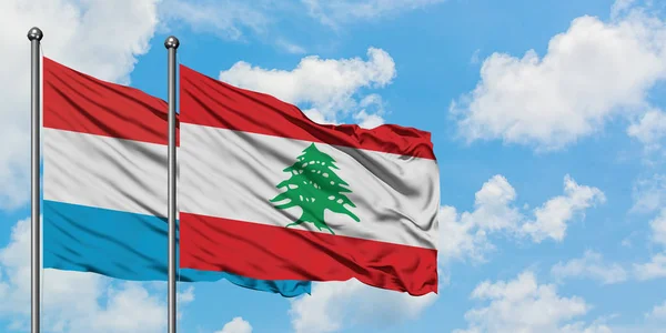 Bandera de Luxemburgo y Líbano ondeando en el viento contra el cielo azul nublado blanco juntos. Concepto diplomático, relaciones internacionales . — Foto de Stock