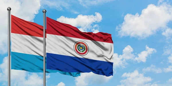 Lussemburgo e Paraguay sventolano insieme la bandiera contro il bianco cielo azzurro nuvoloso. Concetto di diplomazia, relazioni internazionali . — Foto Stock