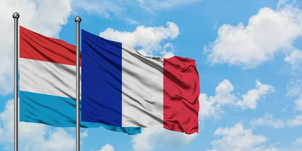Luksemburg i Reunion flaga machając w wiatr przed białym zachmurzone błękitne niebo razem. Koncepcja dyplomacji, stosunki międzynarodowe. — Zdjęcie stockowe