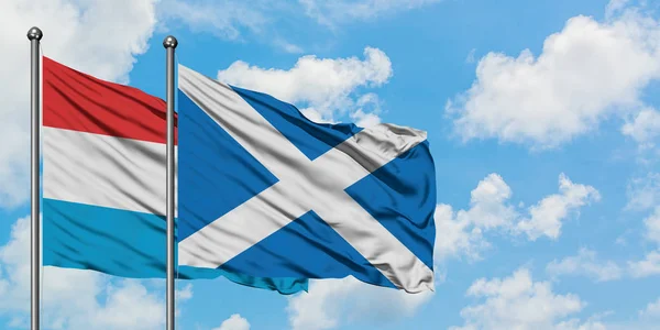 Luxembourg and Scotland flag waving in the wind against white cloudy blue sky together. Diplomacy concept, international relations.