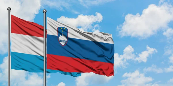 Luxembourg and Slovenia flag waving in the wind against white cloudy blue sky together. Diplomacy concept, international relations. — Stock Photo, Image