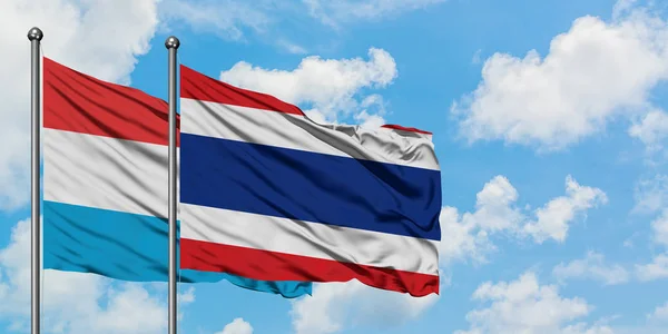 A bandeira do Luxemburgo e da Tailândia agitando no vento contra o céu azul nublado branco juntos. Conceito de diplomacia, relações internacionais . — Fotografia de Stock