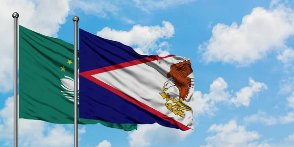 Bandera de Macao y Samoa Americana ondeando en el viento contra el cielo azul nublado blanco juntos. Concepto diplomático, relaciones internacionales . — Foto de Stock