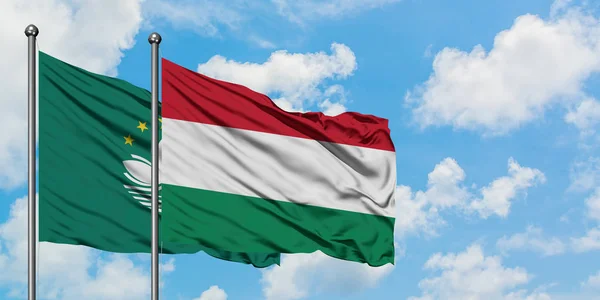Bandera de Macao y Hungría ondeando en el viento contra el cielo azul nublado blanco juntos. Concepto diplomático, relaciones internacionales . — Foto de Stock