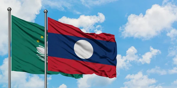 Bandera de Macao y Laos ondeando en el viento contra el cielo azul nublado blanco juntos. Concepto diplomático, relaciones internacionales . — Foto de Stock