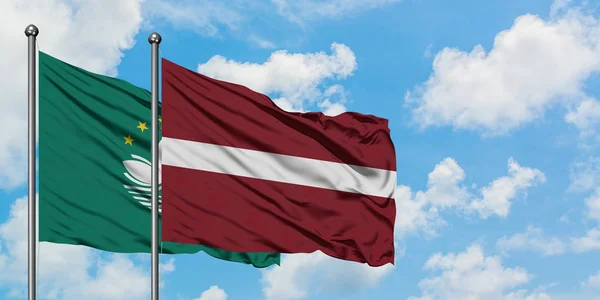 Bandera de Macao y Letonia ondeando en el viento contra el cielo azul nublado blanco juntos. Concepto diplomático, relaciones internacionales . — Foto de Stock