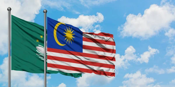 Macao and Malaysia flag waving in the wind against white cloudy blue sky together. Diplomacy concept, international relations.