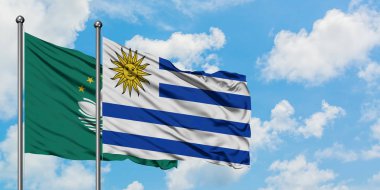 Macao ve Uruguay bayrağı birlikte beyaz bulutlu mavi gökyüzüne karşı rüzgarda sallayarak. Diplomasi kavramı, uluslararası ilişkiler.