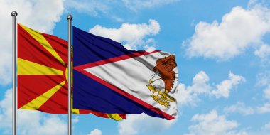 Makedonya ve Amerikan Samoası bayrağı birlikte beyaz bulutlu mavi gökyüzüne karşı rüzgarda sallayarak. Diplomasi kavramı, uluslararası ilişkiler.