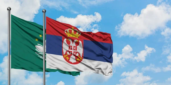 Bandera de Macao y Serbia ondeando en el viento contra el cielo azul nublado blanco juntos. Concepto diplomático, relaciones internacionales . — Foto de Stock