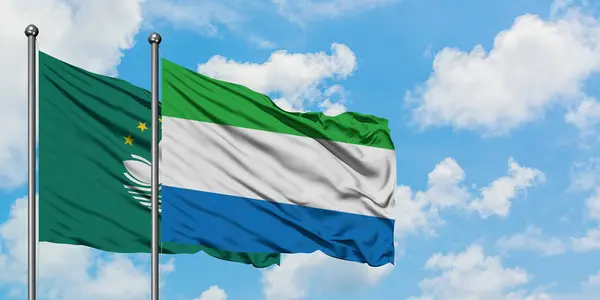 Macao und Sierra Leone schwenken gemeinsam die Flagge im Wind vor dem wolkenverhangenen blauen Himmel. Diplomatie-Konzept, internationale Beziehungen. — Stockfoto