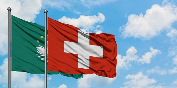 Macaa a Švýcarsko vlají ve větru proti bíle zatažené modré obloze. Diplomacie, mezinárodní vztahy. — Stock fotografie
