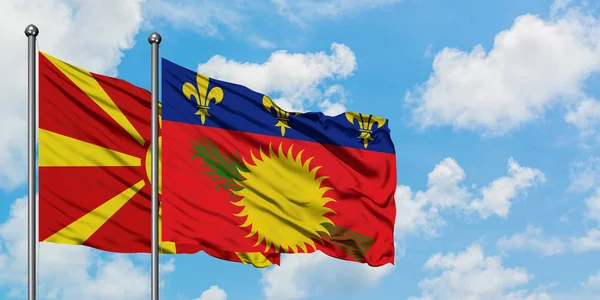 Bandera de Macedonia y Guadalupe ondeando en el viento contra el cielo azul nublado blanco juntos. Concepto diplomático, relaciones internacionales . — Foto de Stock