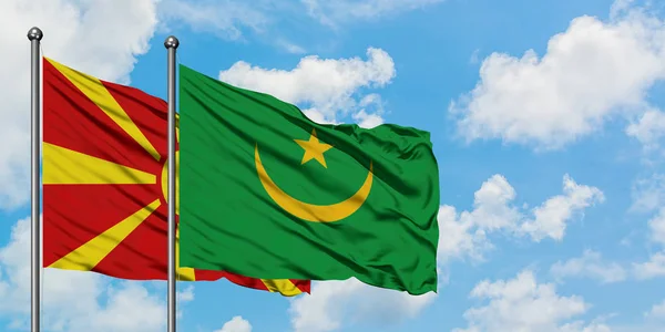 Bandera de Macedonia y Mauritania ondeando en el viento contra el cielo azul nublado blanco juntos. Concepto diplomático, relaciones internacionales . — Foto de Stock