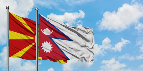 Bandera de Macedonia y Nepal ondeando en el viento contra el cielo azul nublado blanco juntos. Concepto diplomático, relaciones internacionales . — Foto de Stock